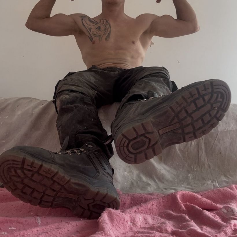 Master Dra1ns in muddy work trousers, boot soles to the camera